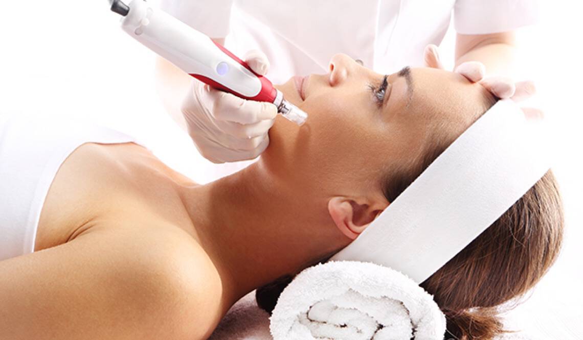 A woman getting a microneedling skin treatment done by a professional